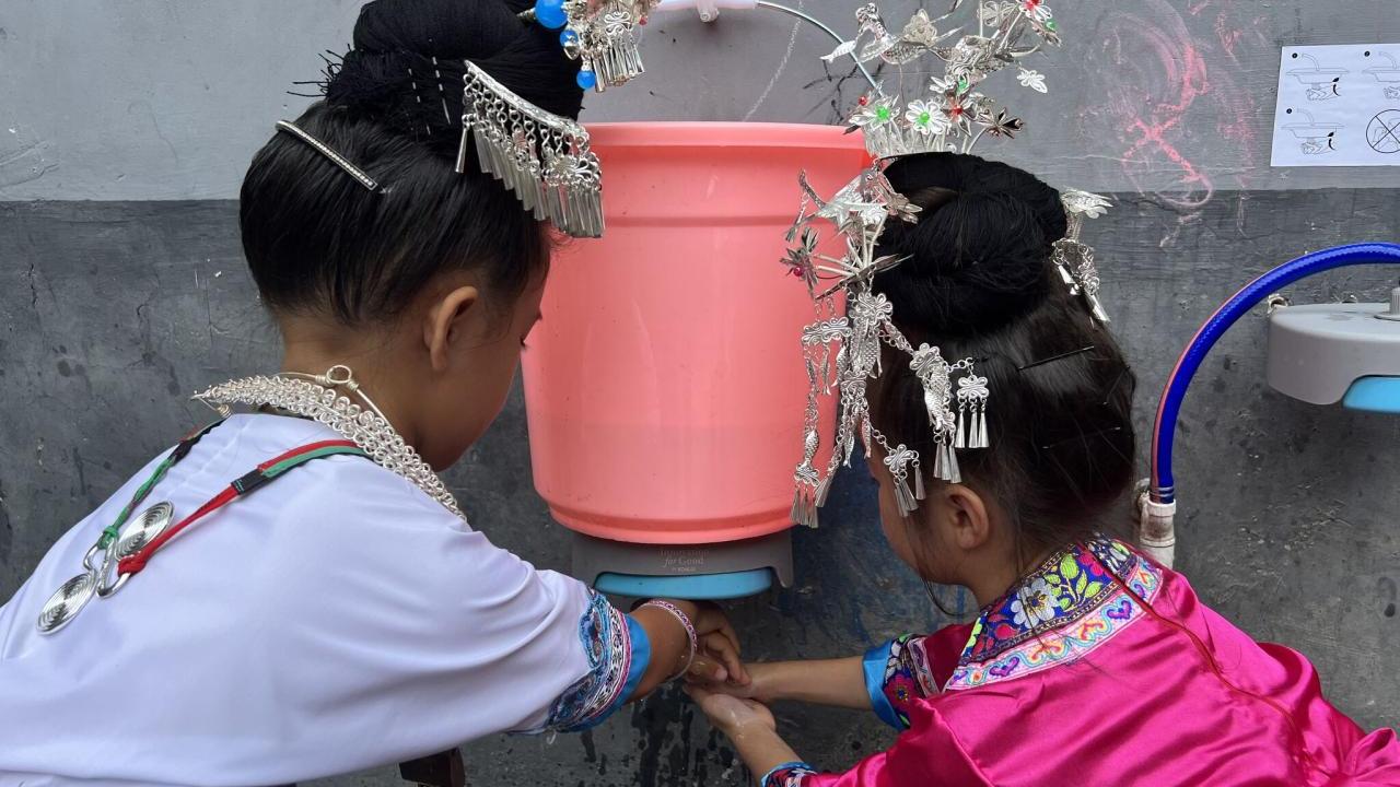 girls in traditional dress washing their hands