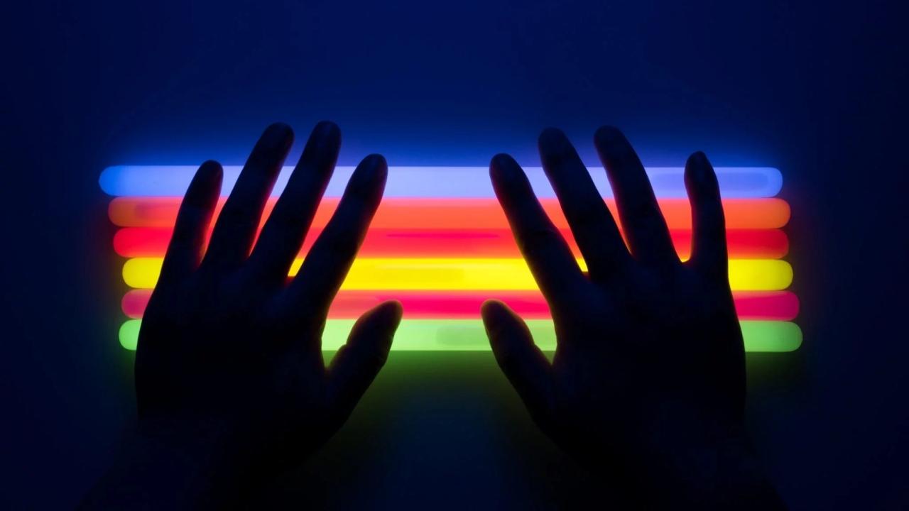 two hands back-lit by a rainbow of colors