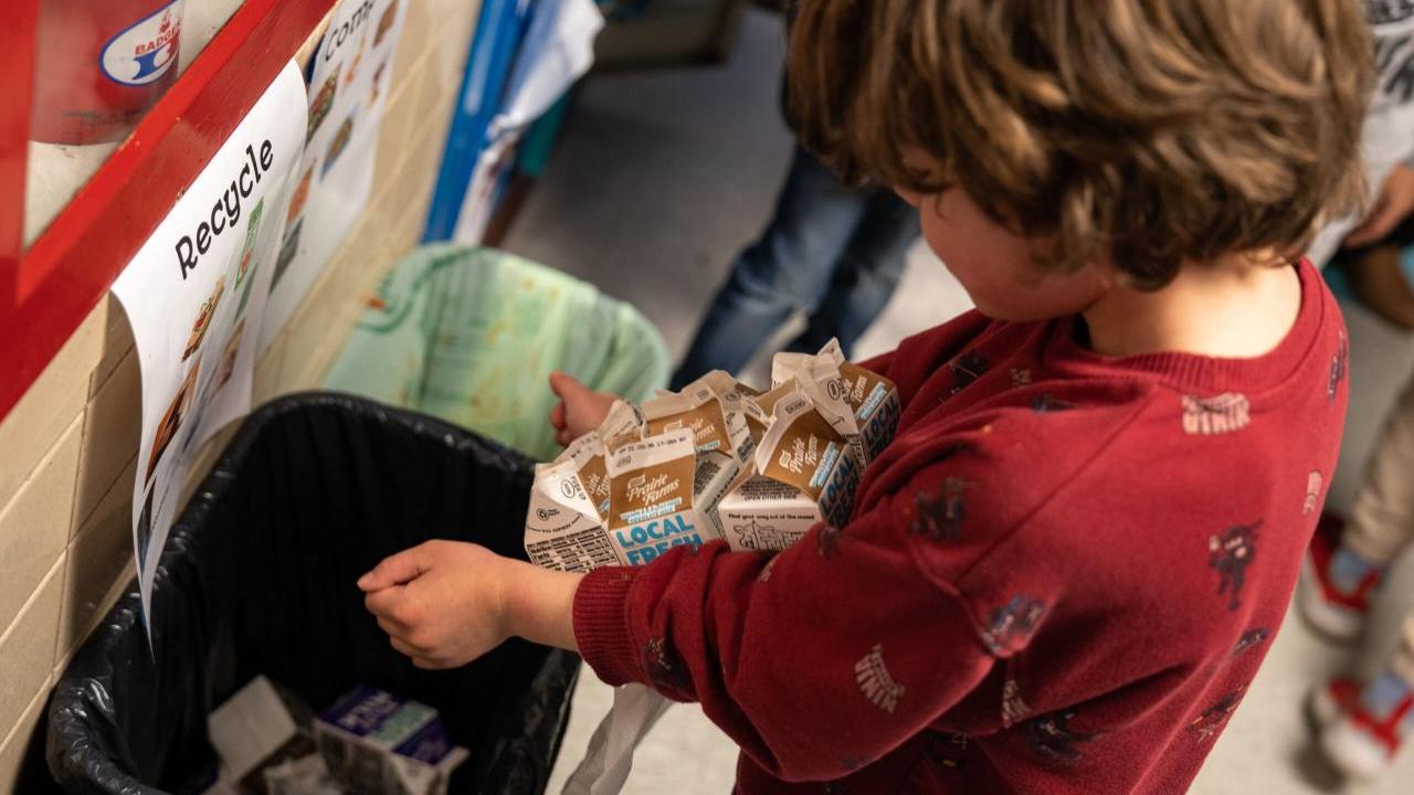 child recycling a carton