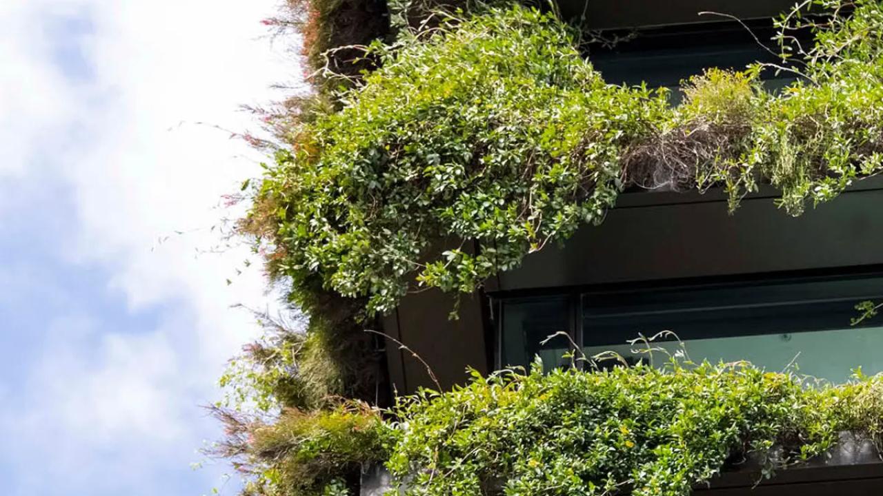 A multi-story building with overflowing plants on every balcony.