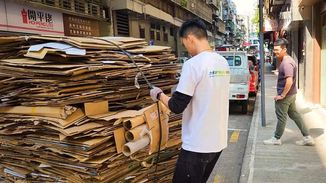A person tying up a large bale of cardboard.