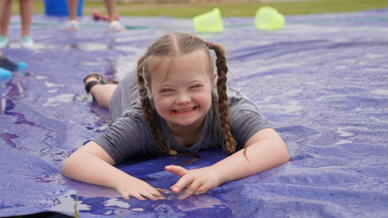 A child playing on a wet slide on the ground
