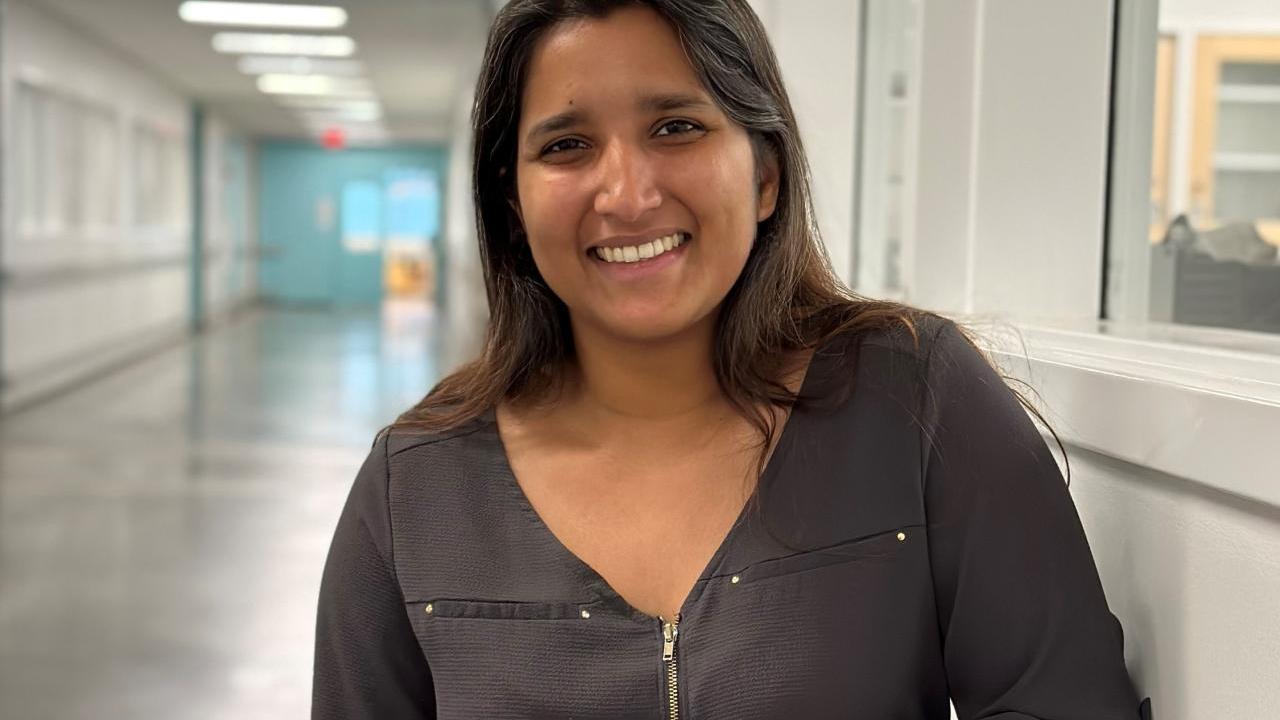 Woman standing in the corridor of an R&D lab looking at the camera and smiling.