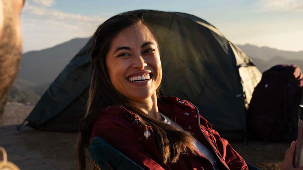 Person sat in front of a tent smiling 