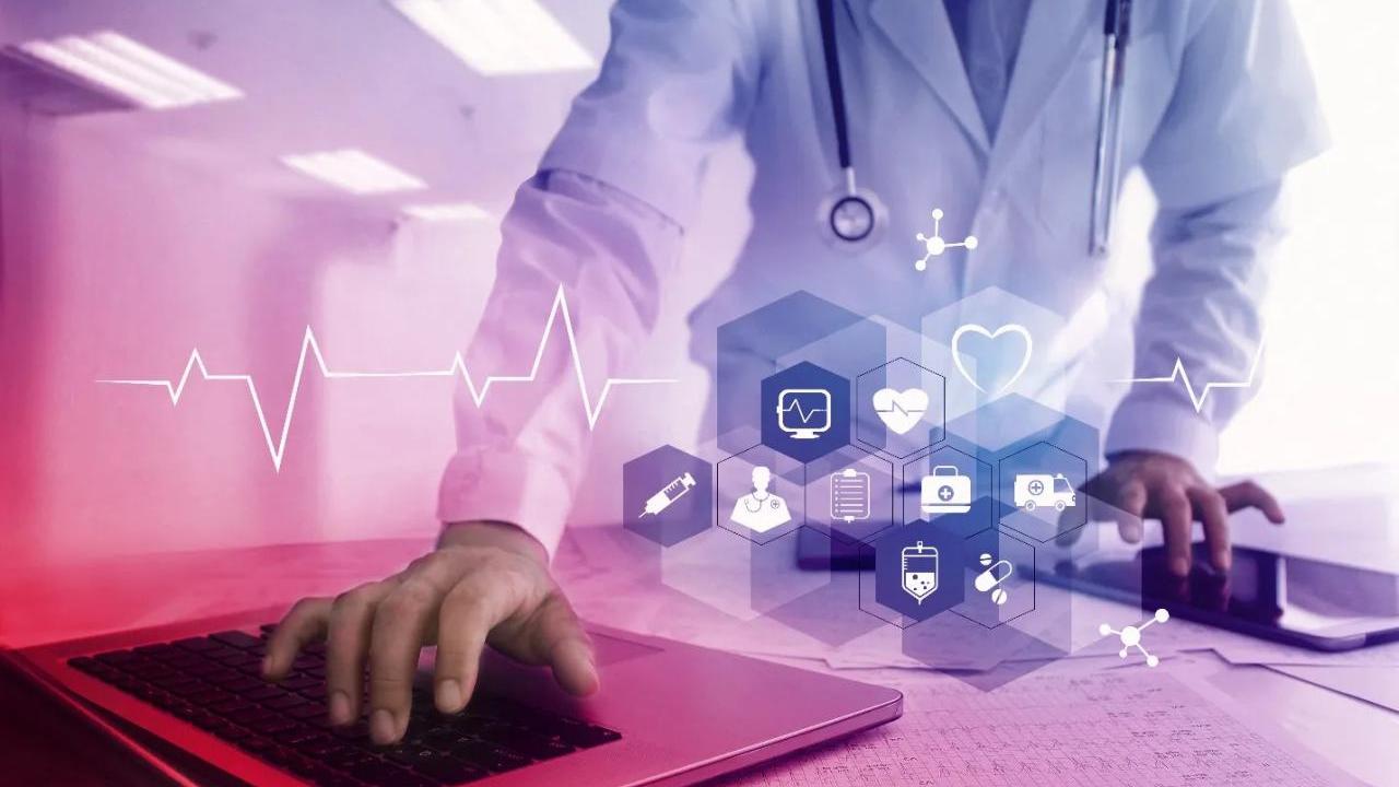 A person in medical gear using a laptop.