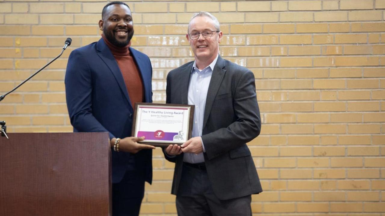Two people holding a plaque behind a podium.