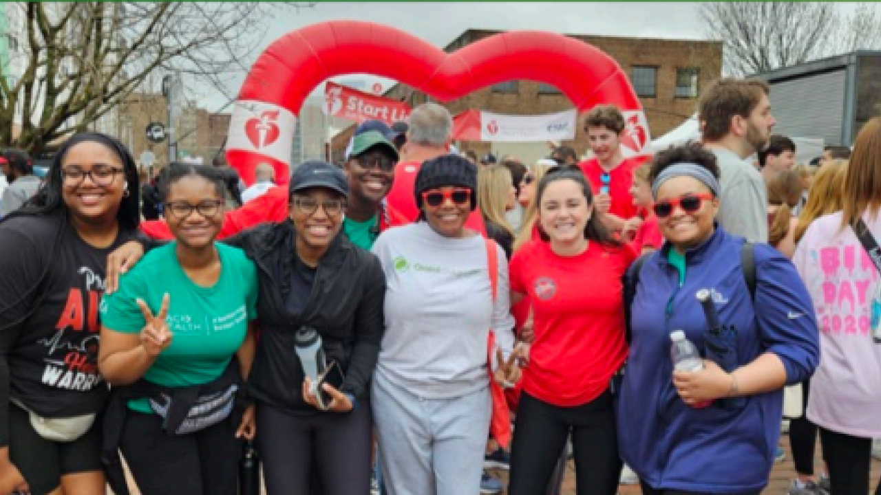 A group posed outside, a heart shaped balloon in the background.
