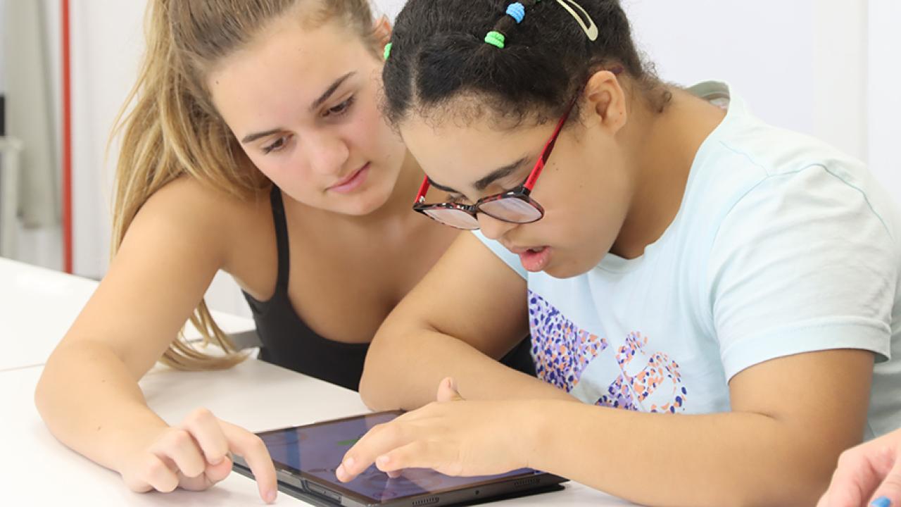 A person using a table with another assisting them