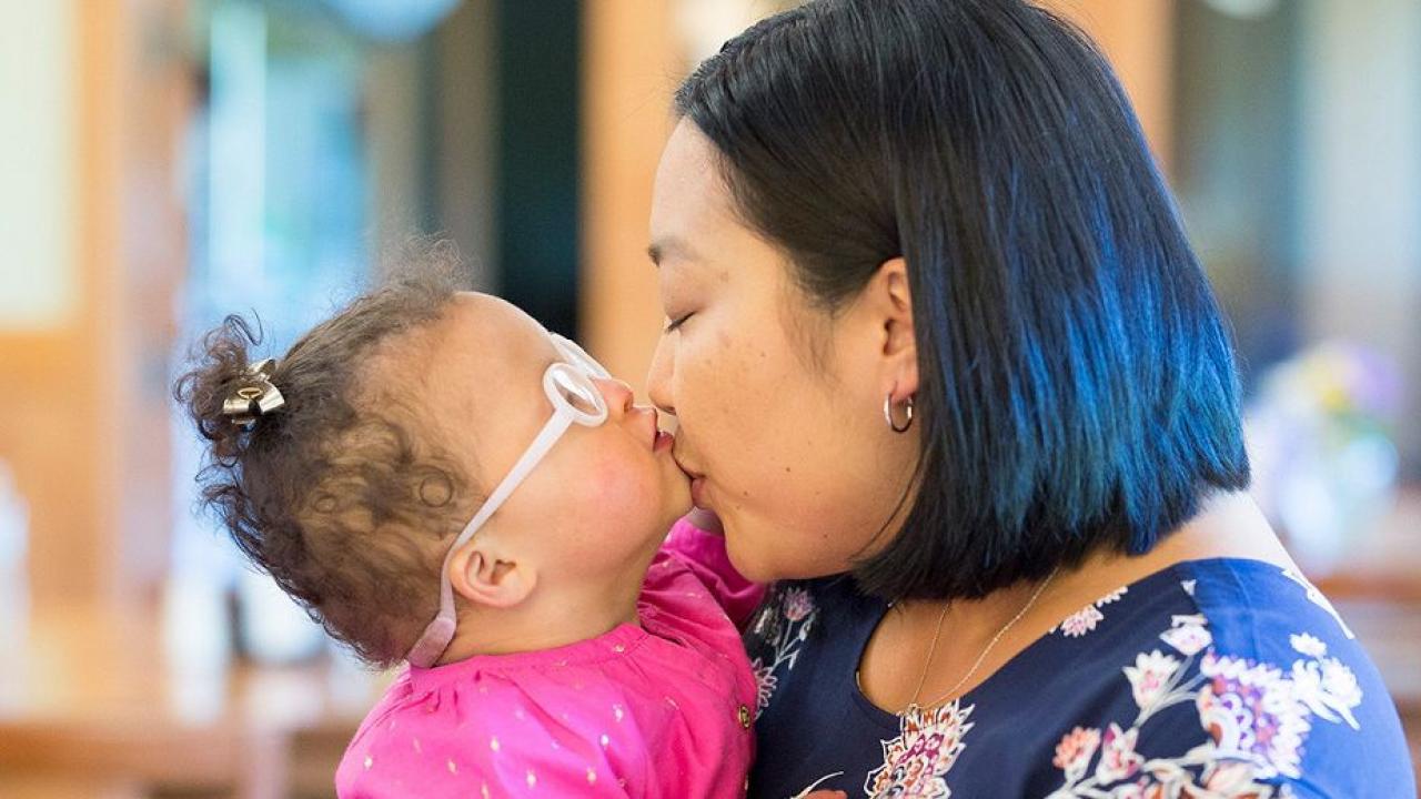 Person holding a child wearing glasses