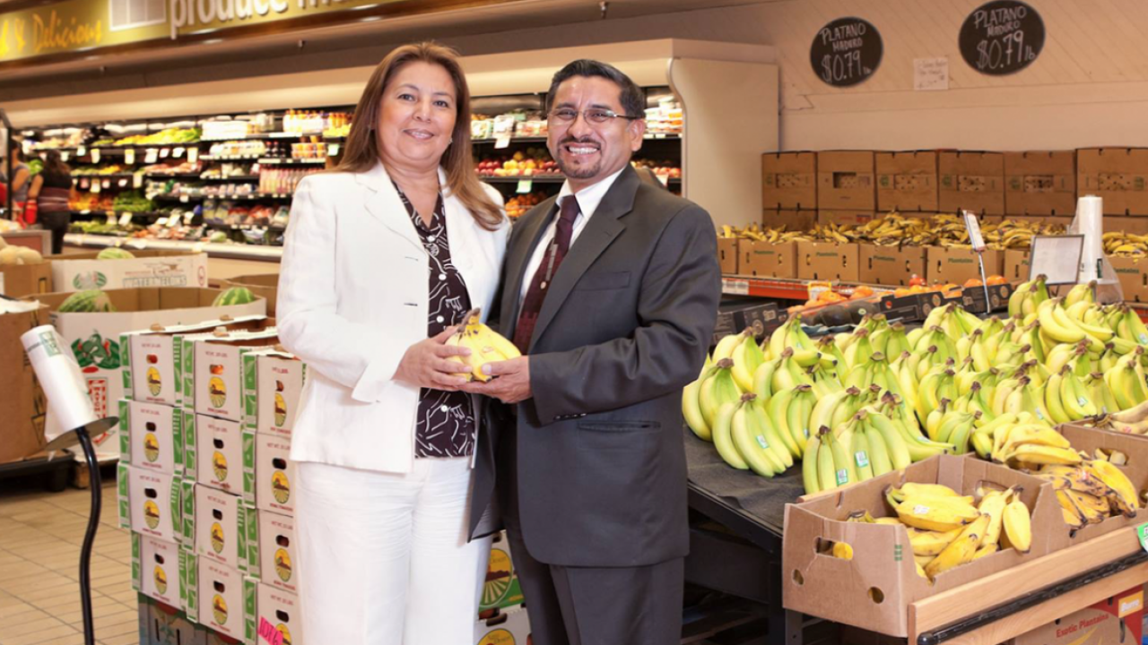 two people standing in the grocery store holding plantains