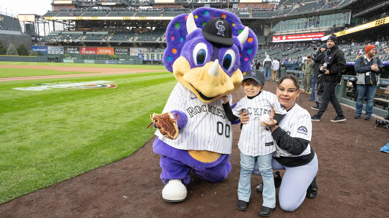 Colorado Rockies mascot with a child and adult on a baseball field