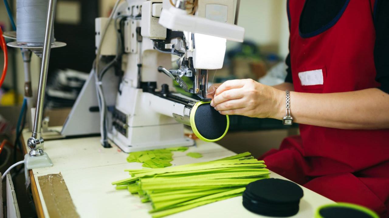Worker in a factory sewing on a zipper