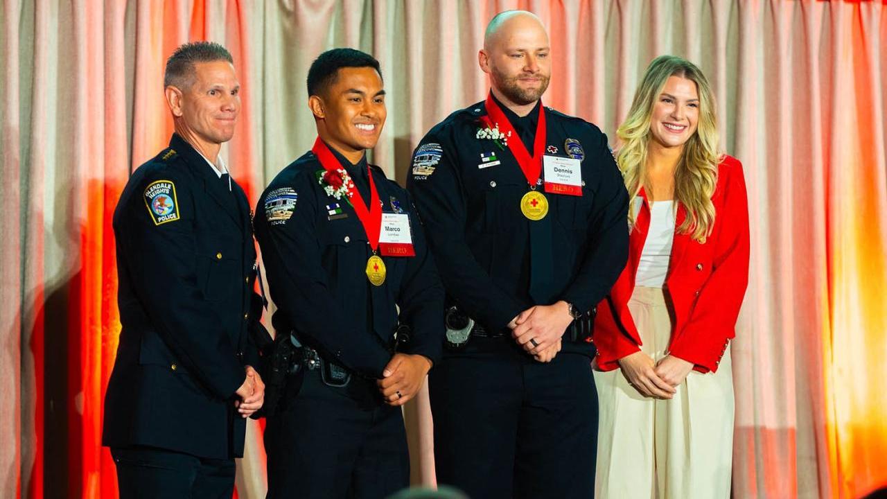 Four people on a stage, three in uniform.
