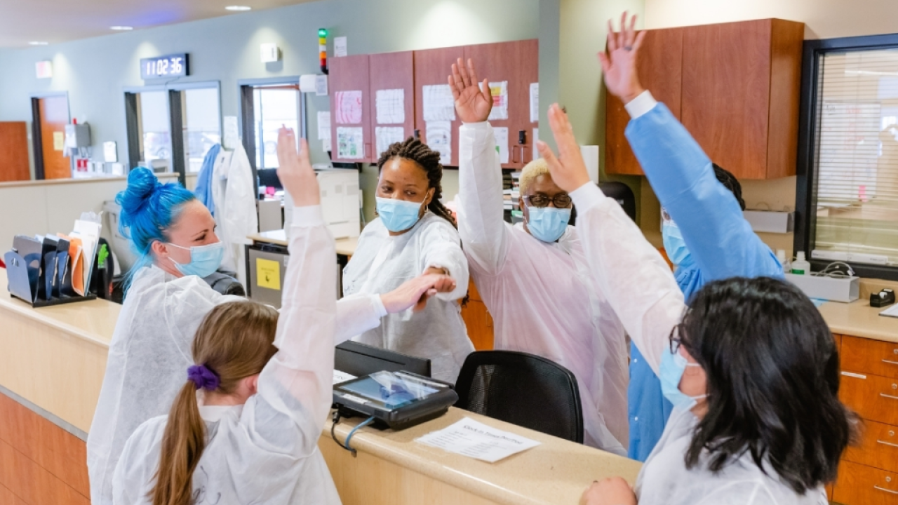 nurses raising their hands at a nursing station