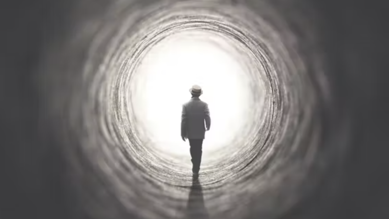 silhouette of person approaching the light at the end of a dark tunnel