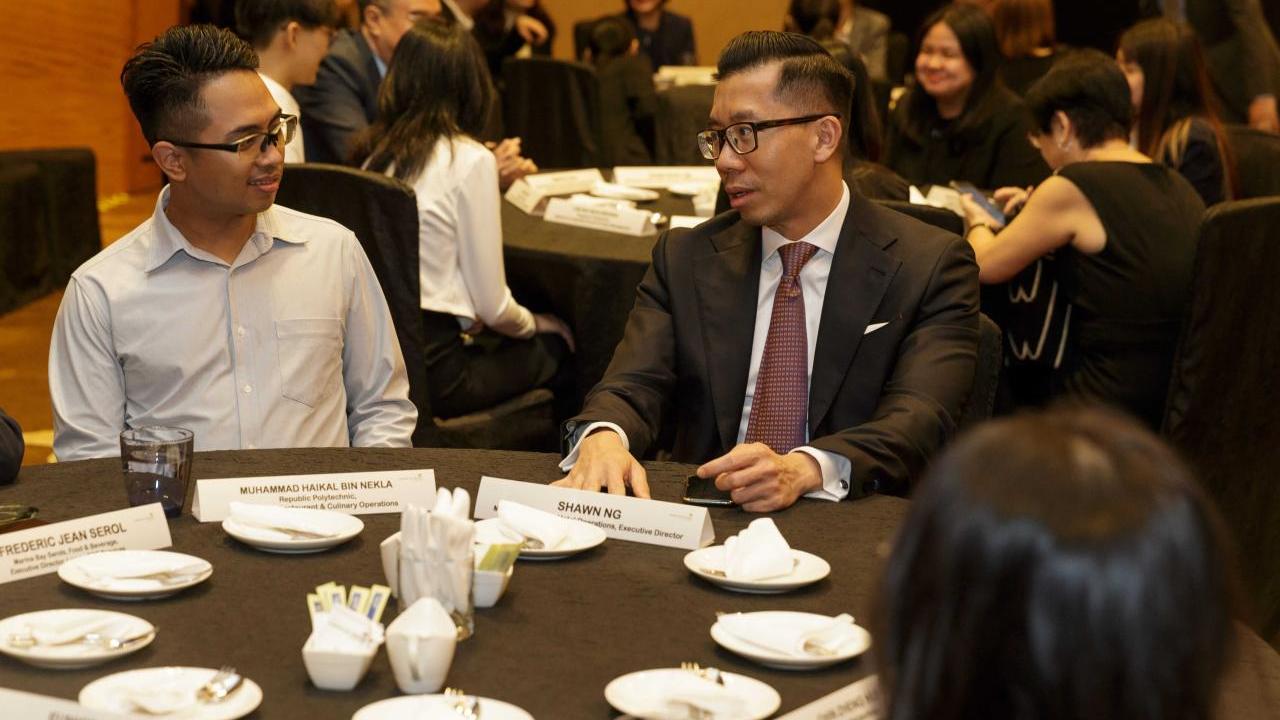 People sitting together and talking at a round dinner event table