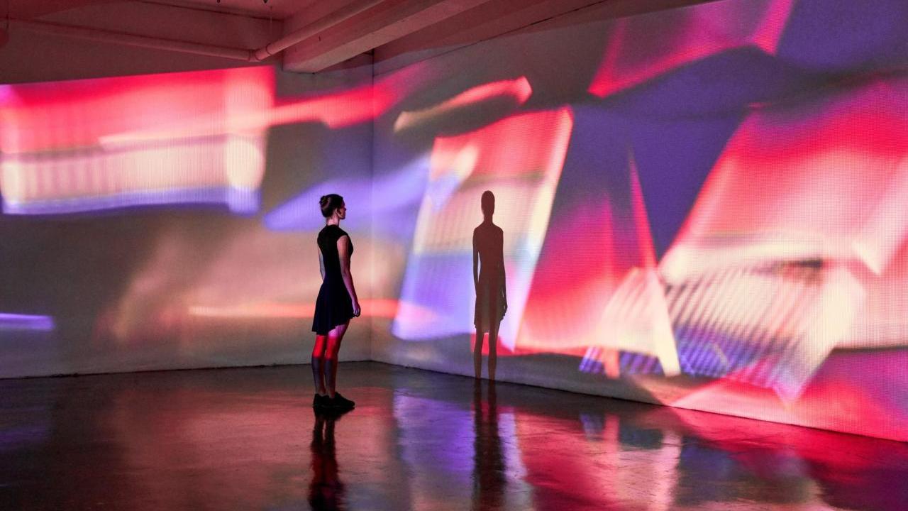 person looking at their shadow in a room with lights
