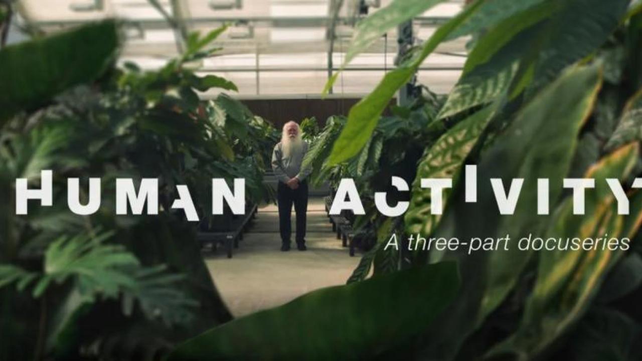 A person standing in the distance in a lush greenhouse. "Human Activity A three part docuseries" in broken letters on top.
