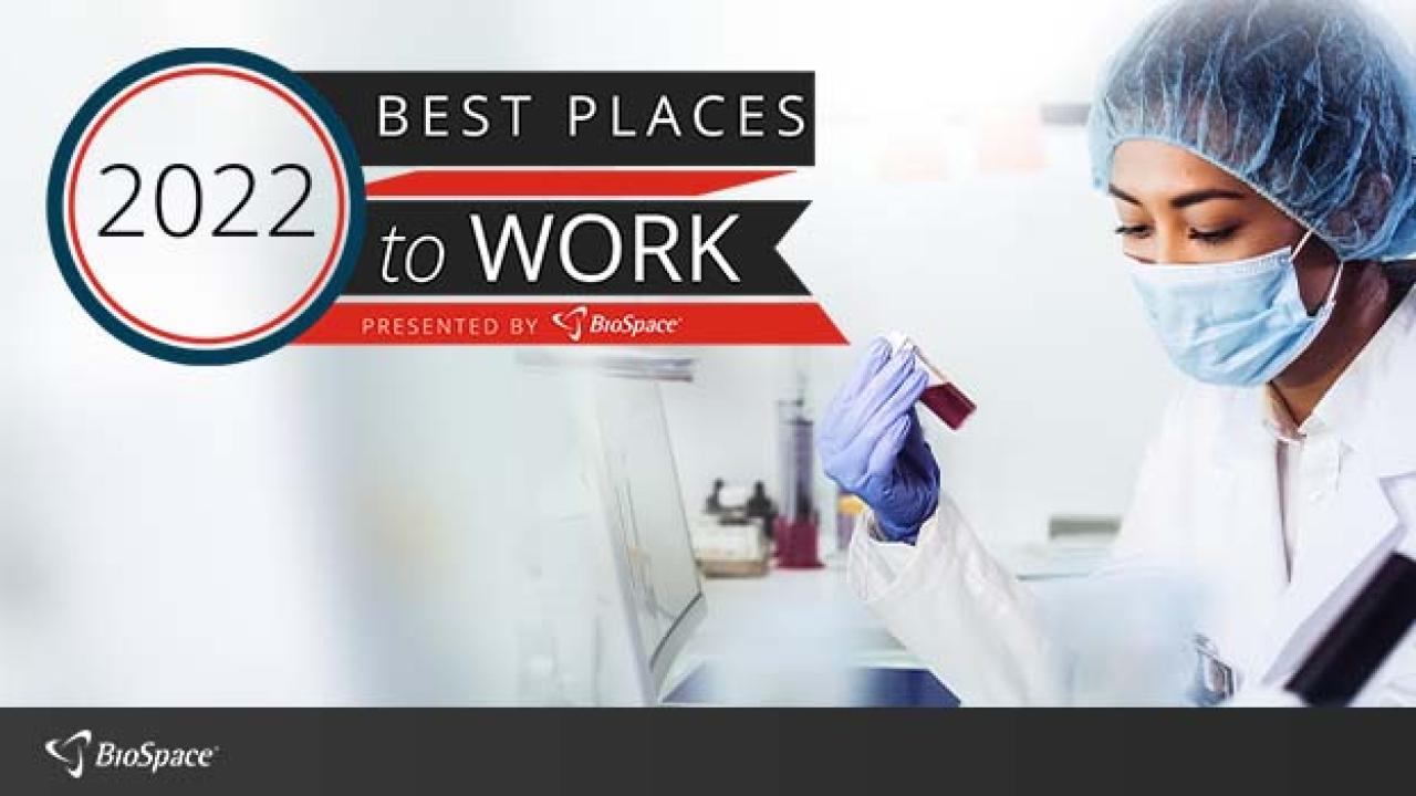 Gowned and masked scientist holding a test tube. Award banner for Best Places to work.