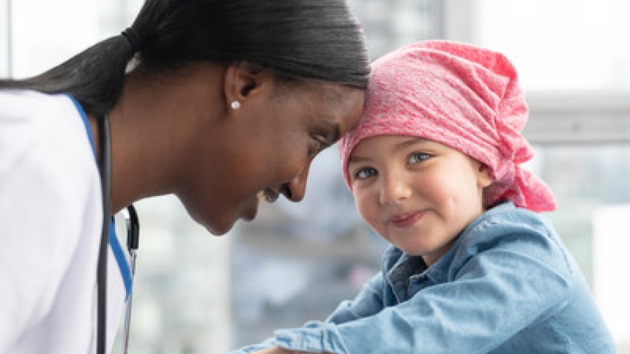 Female doctor is bumping heads with a young cancer patient.