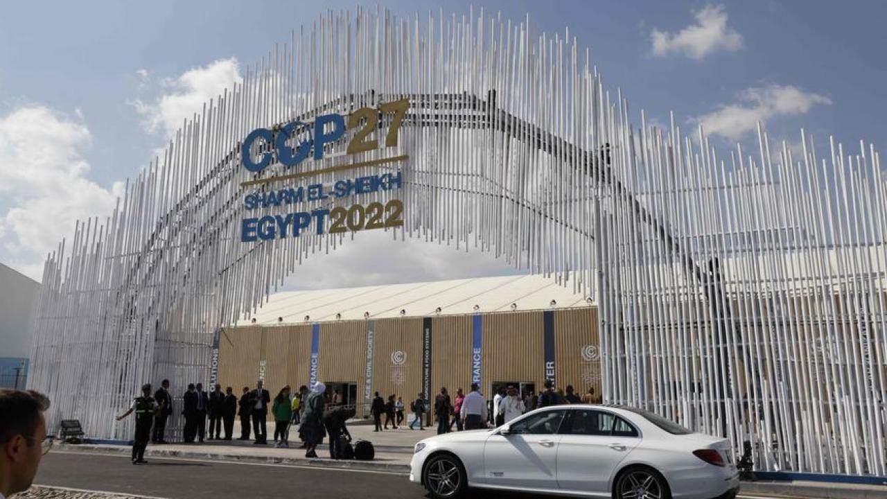 People walking in front of COP27 arch