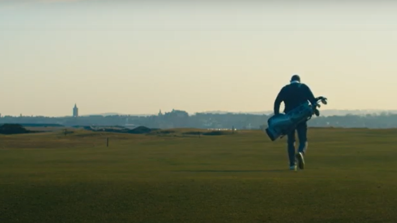 Rear view of caddy walking with golf clubs