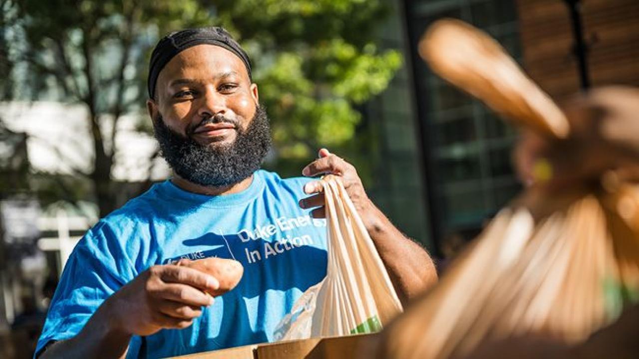 A volunteer packing a bag with food outside.