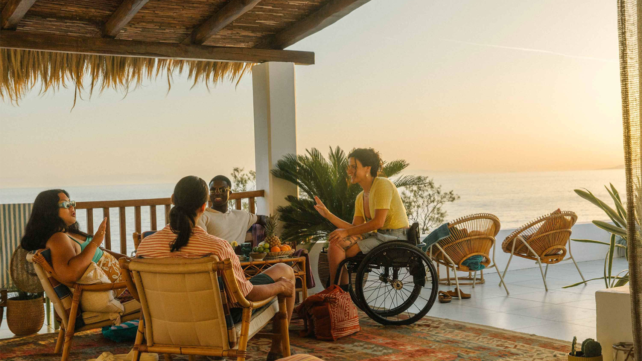 A group seated in a covered area overlooking an ocean expanse.