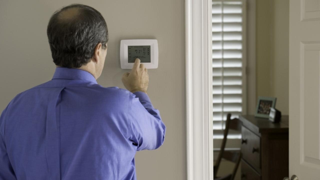 Someone adjusting a thermostat