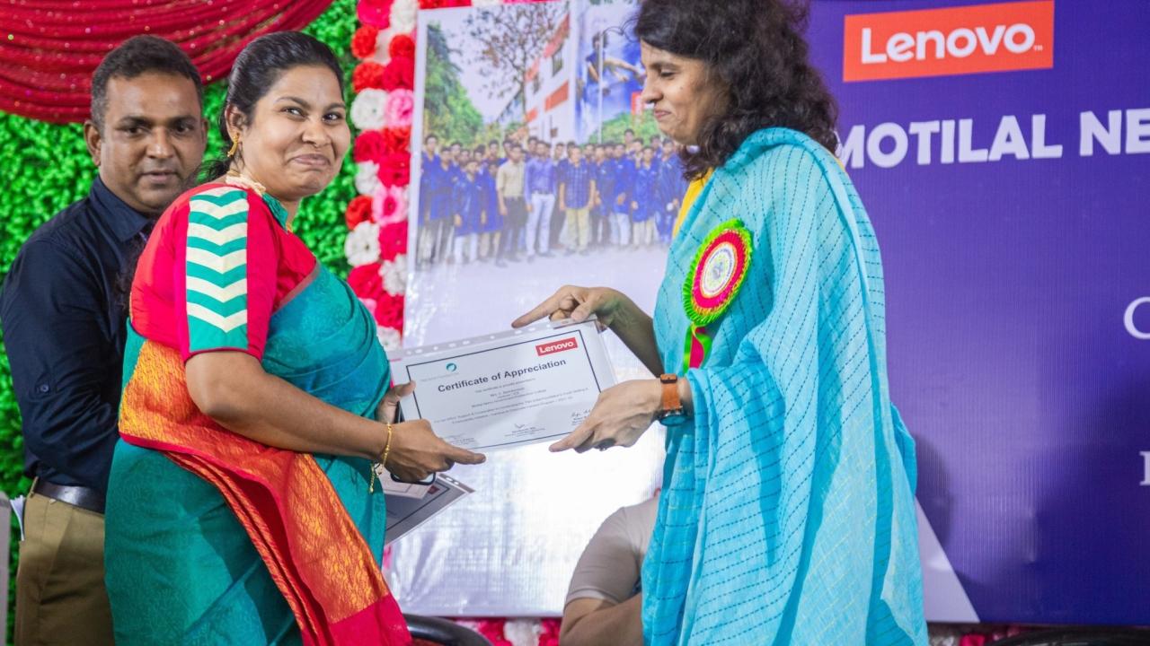a person accepting a certificate from another, a large colorful banner behind them