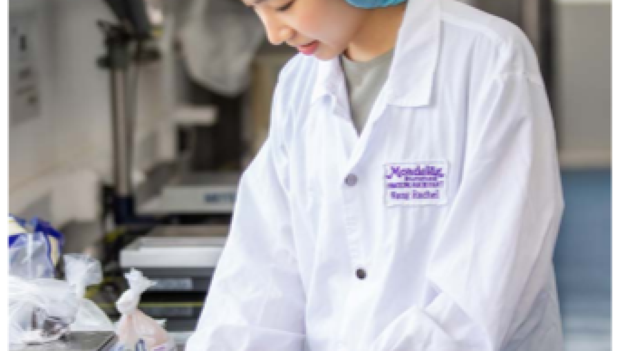 A person in protective lab gear making a note.