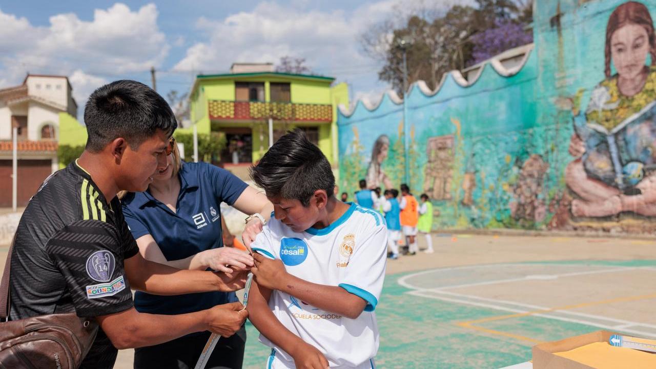 Two adults measuring a child's arm
