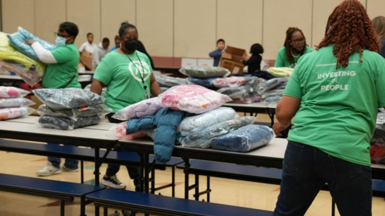 International Paper volunteers place coats on school cafeteria tables