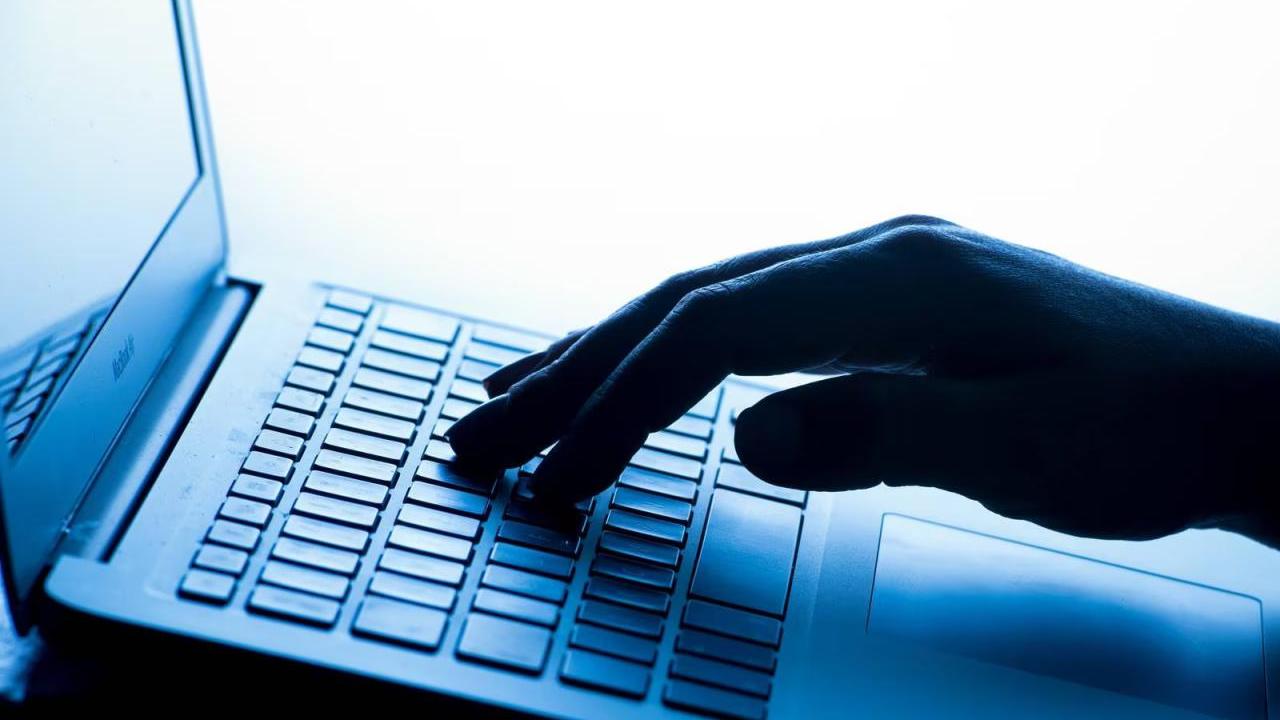 A hand typing on a laptop keyboard.