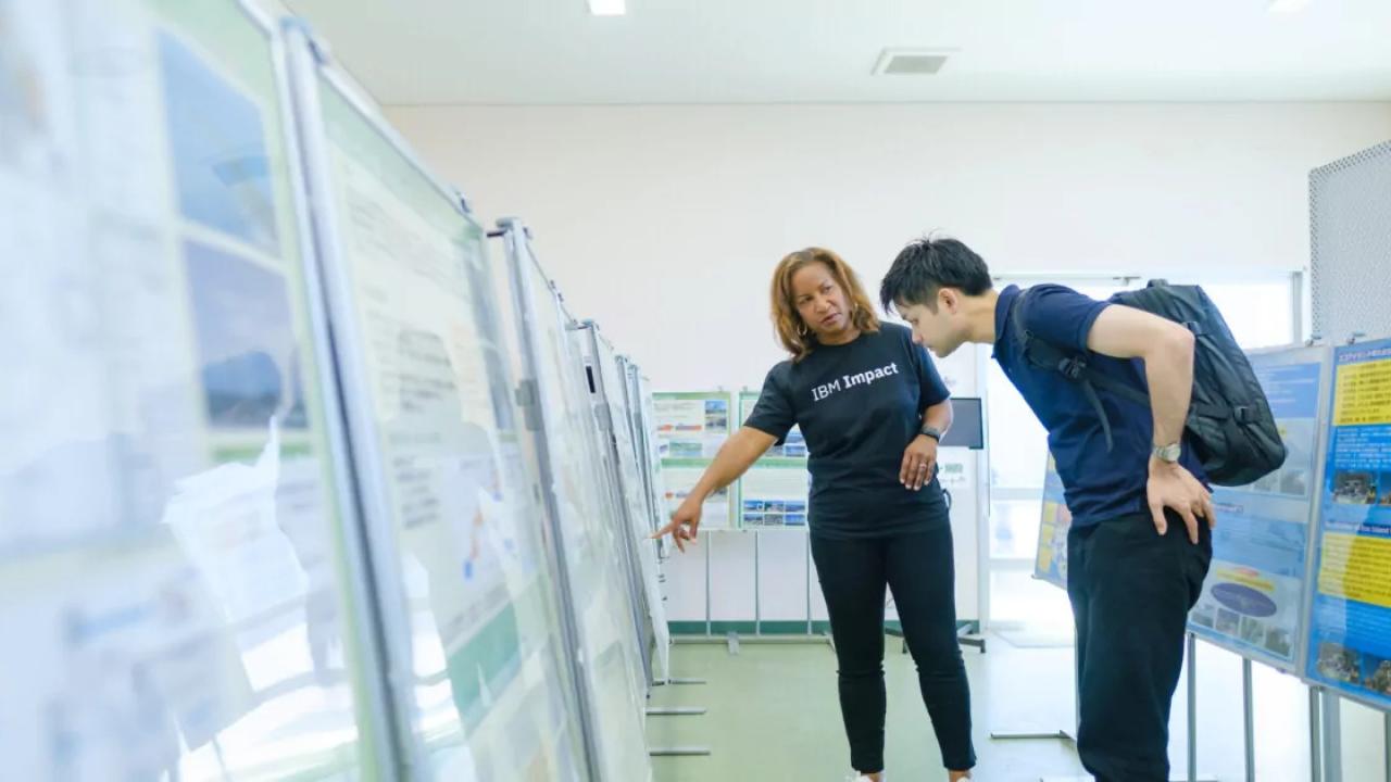 Takahito Motonaga and another looking at rows of boards set up in a room.
