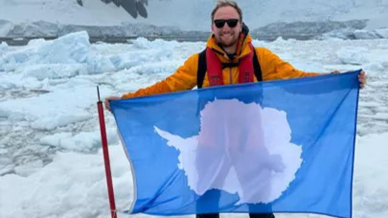 Josh Hasdell holding an Antarctica flag.