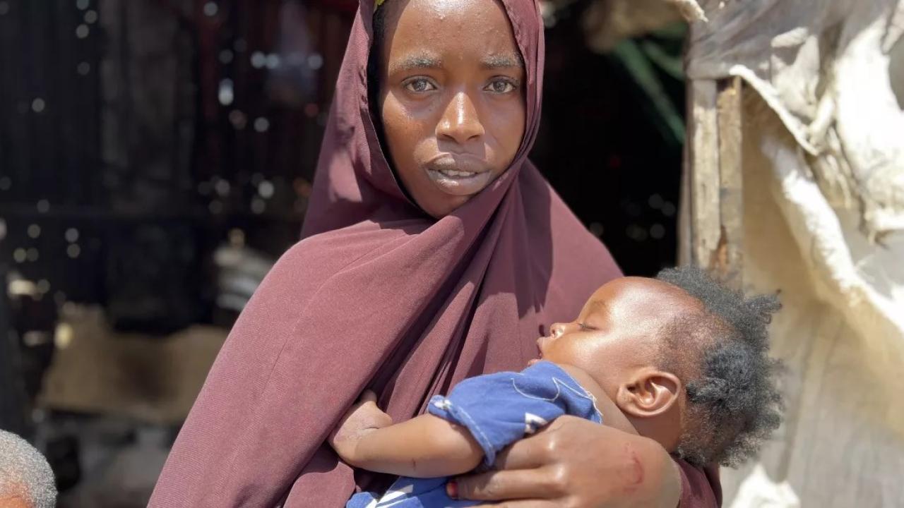 Woman looks at camera while holding baby