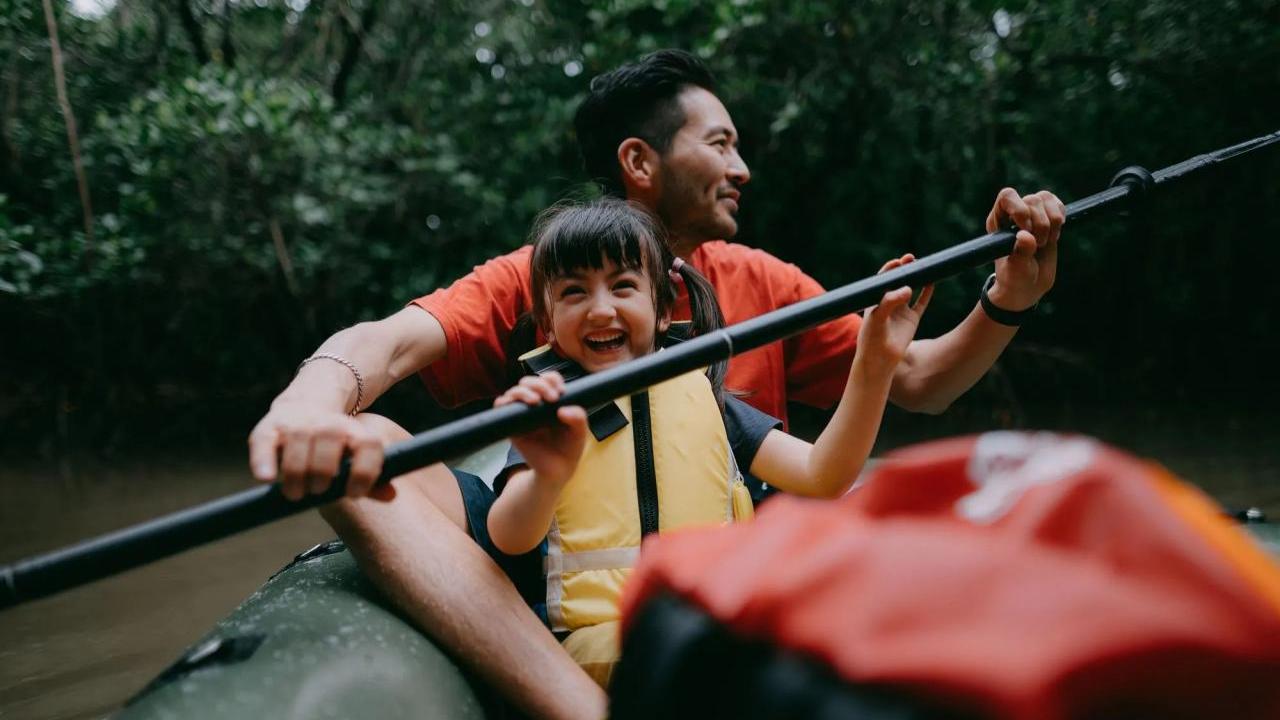 An adult and child kayaking in a body of water.