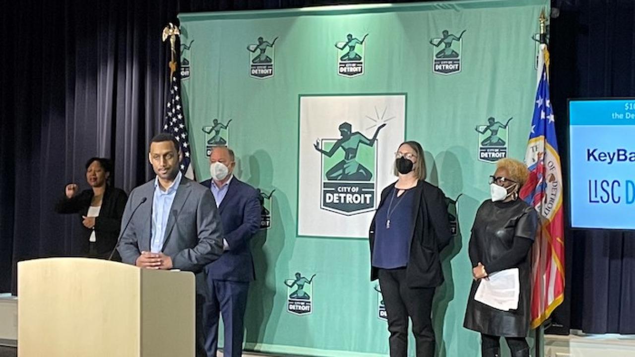 Mayor Duggan of Detroit speaking from a podium. KeyBank LISC banner is behind him. Two males and two females stand behind him to the left and right.