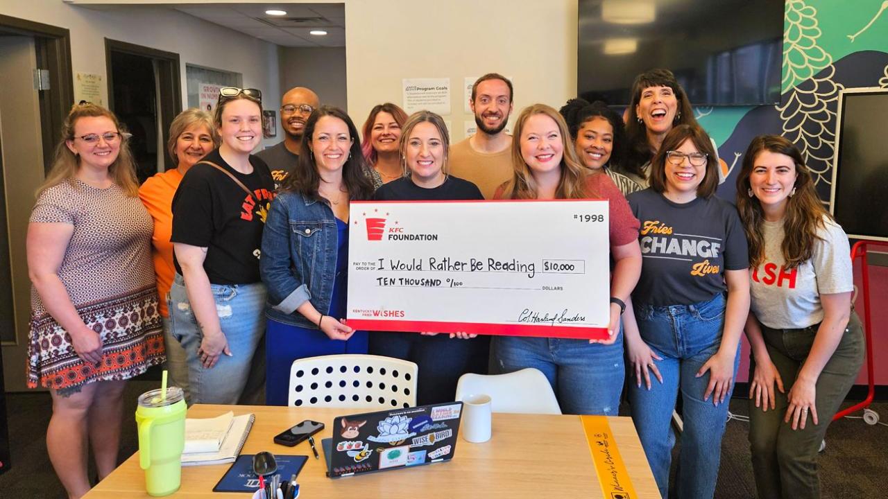 A group posed with a large check