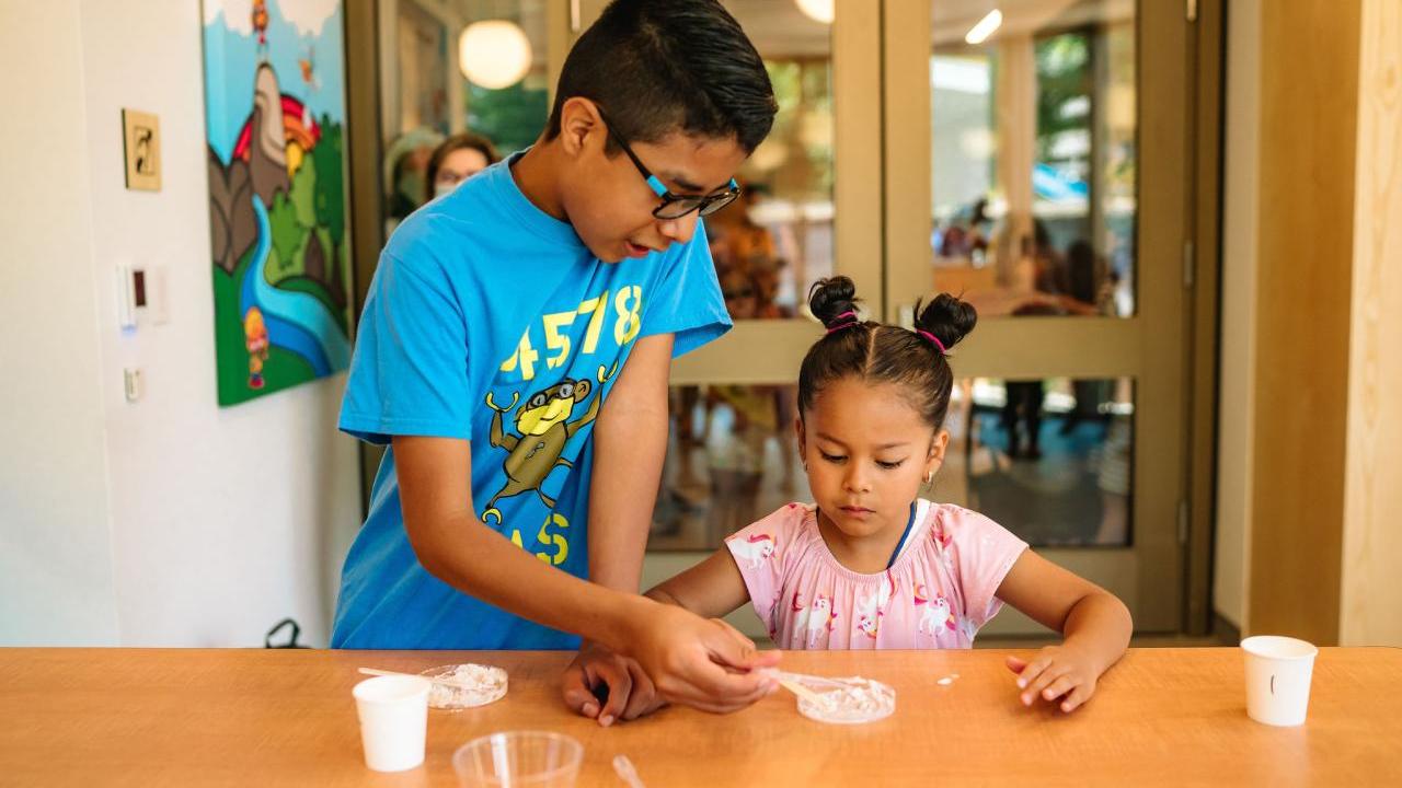 Two kids working together on an experiment on a table