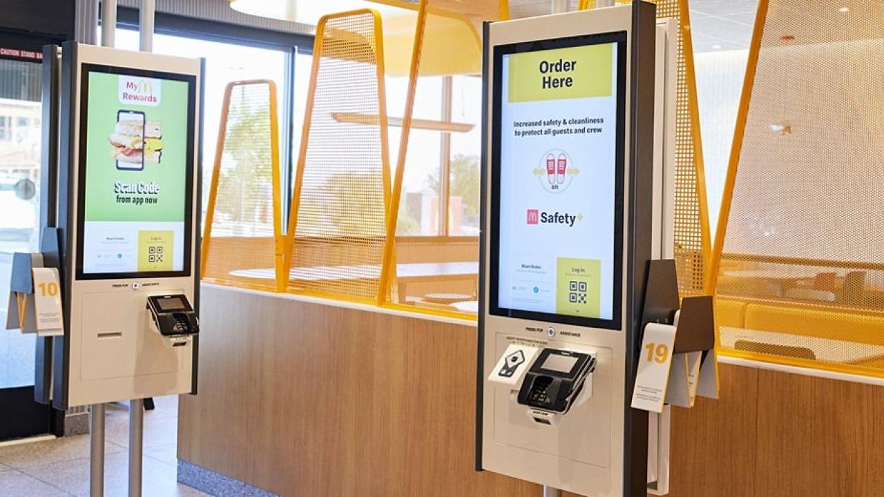 Inside a McDonalds restaurant, two digital kiosks.