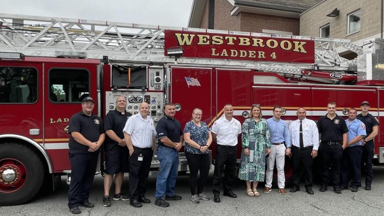 A group posed in front of a fire truck outside.