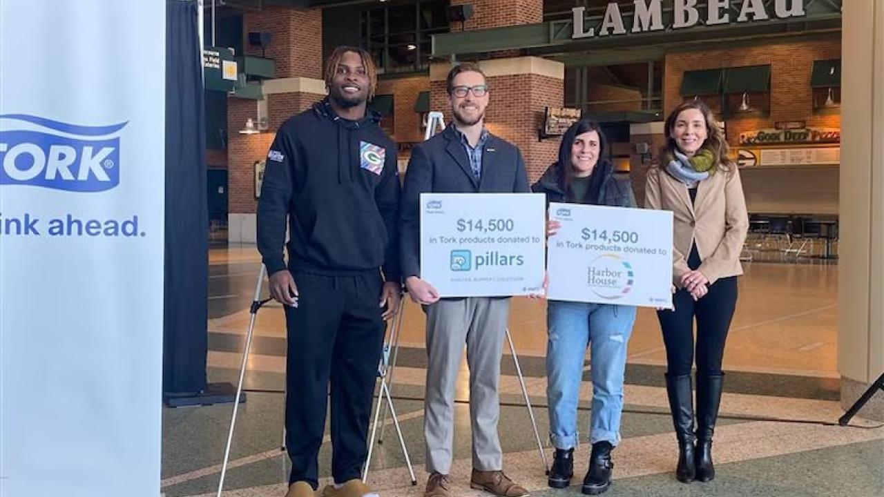 Representatives from The Green Bay Packers and Tork shown holding signs for the $14,500 that was donated.