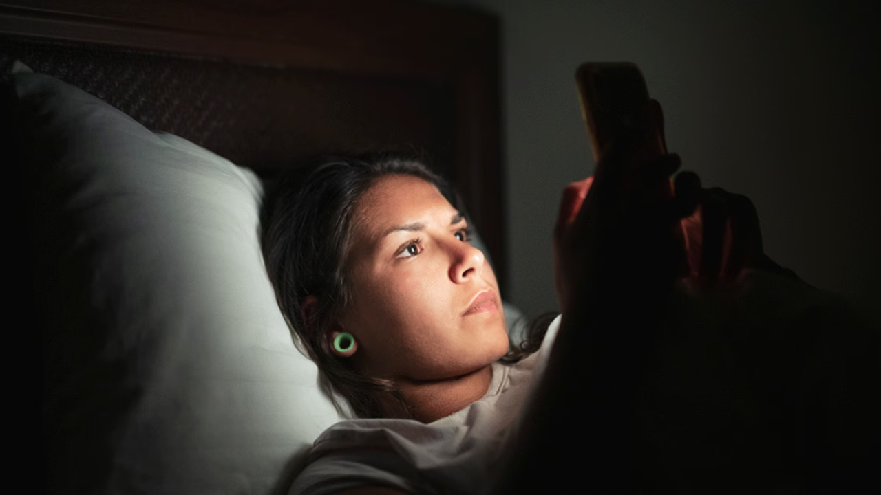 person looking at smartphone at night in bed