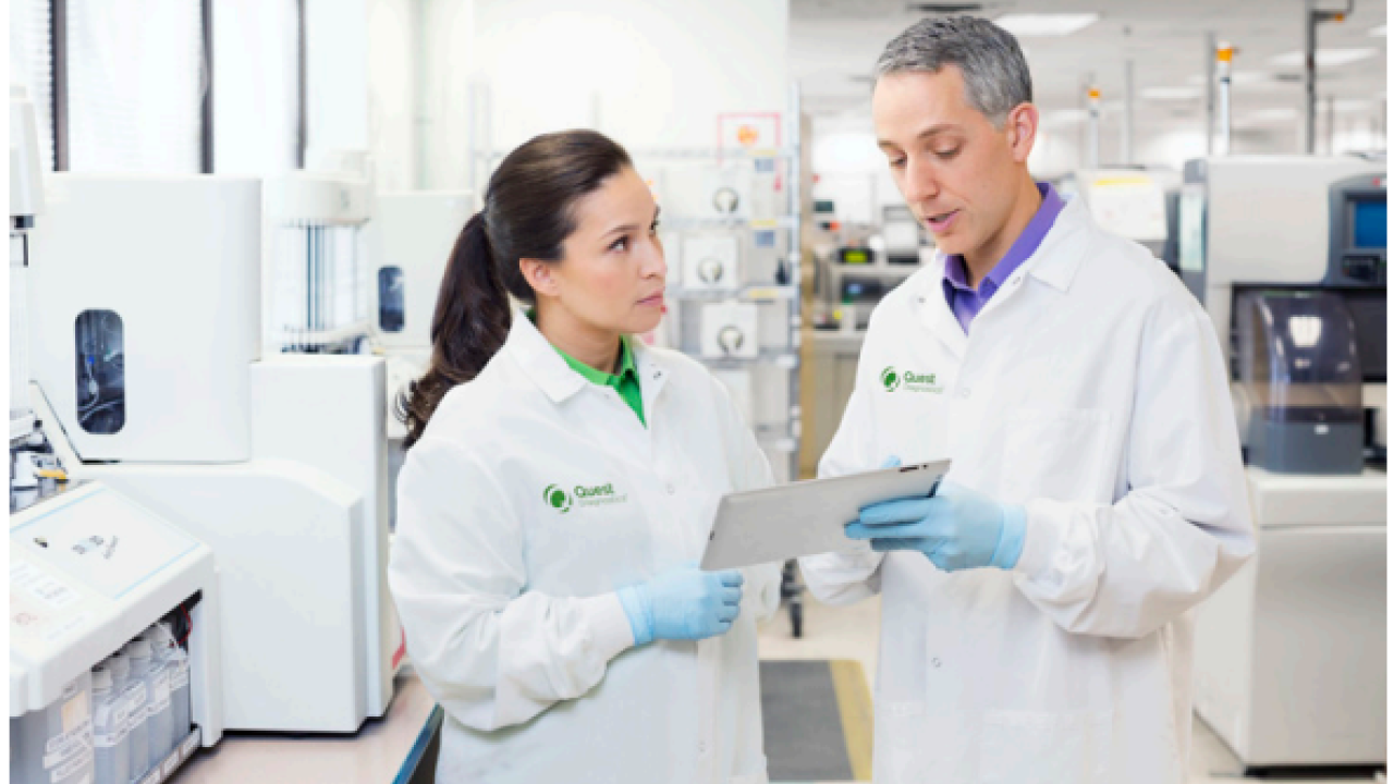 Two people in lab coats talking.