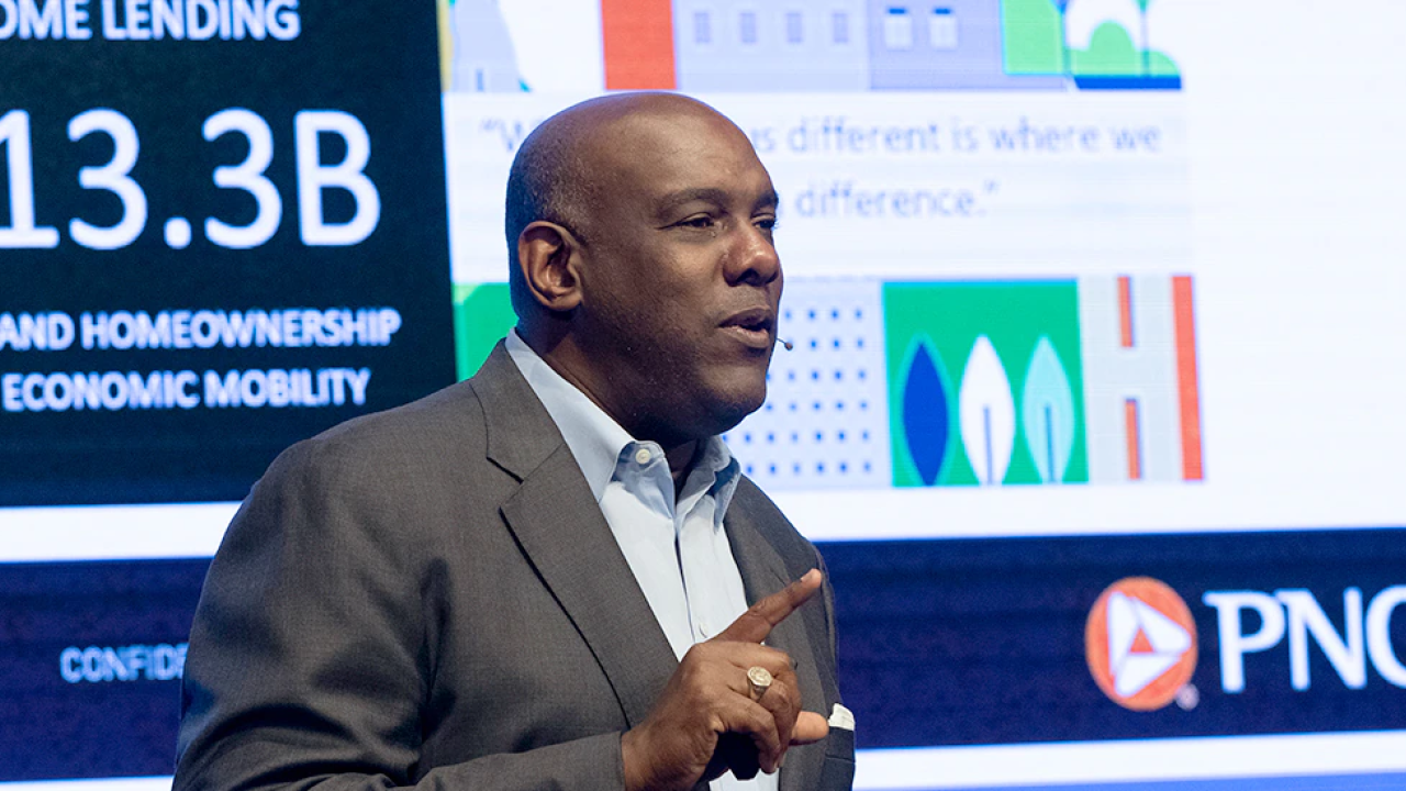 A person speaking with a large display behind them with PNC logo and "Home lending $13.3 B to expand homeownership and economic mobility" visible
