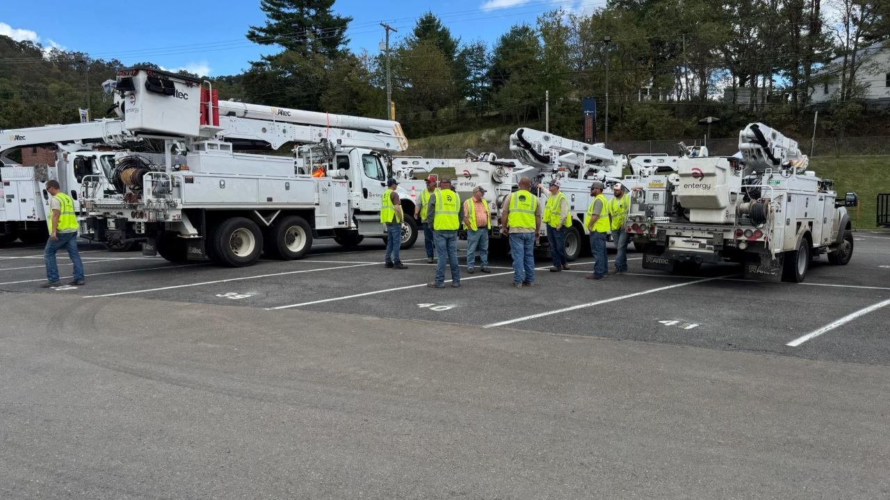 Employees in high-vis vests gathered next to parked bucket trucks.