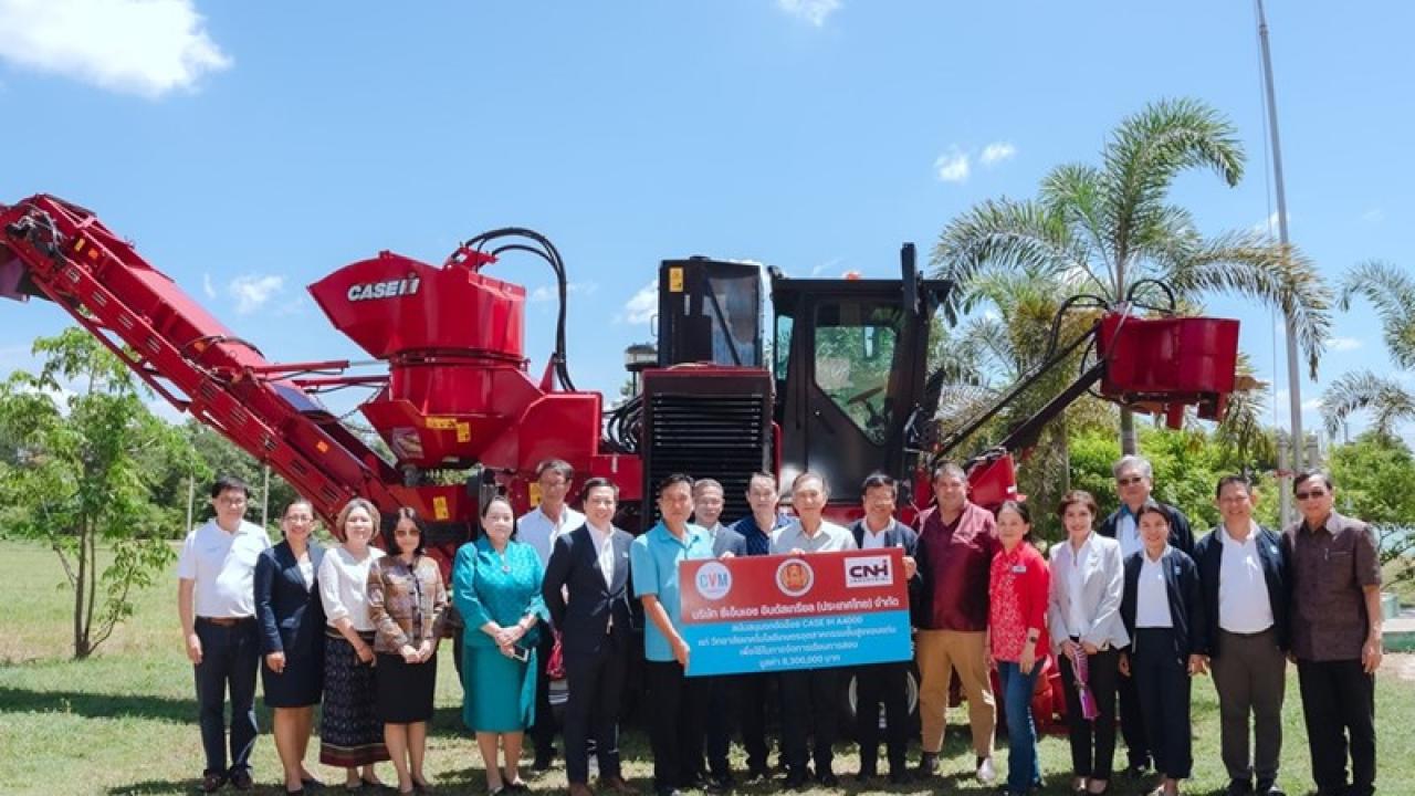 Group of people stood in front of a piece of agricultural machinery 