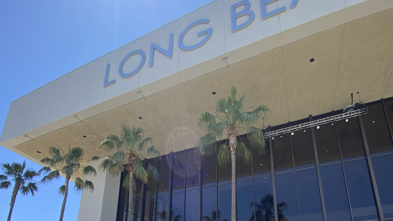 The outside of a 'Long Beach' building that has palm trees outside the windows 